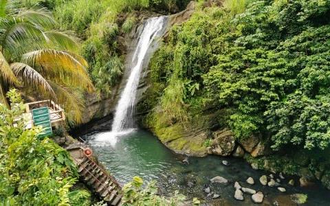 Scenic waterfall with lush vegetation and viewing platform, ideal for tourism and relaxation