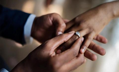 Close-up of a marriage proposal with a diamond ring being placed on a finger.