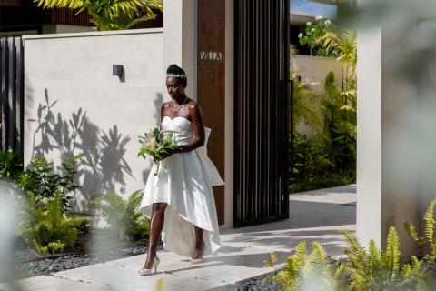 Bride in white dress at Villa 3 with bouquet under sunlit palms