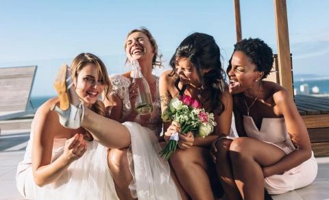 Joyful wedding celebration with bride and friends by the ocean.