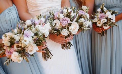 Wedding photo with bride in white and bridesmaids in blue holding bouquets