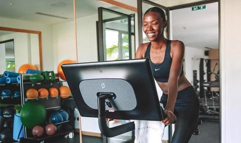 Happy woman in sportswear cycling indoors at a sunny well-equipped gym