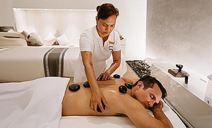 Therapist using hot stones for back massage in tranquil spa setting