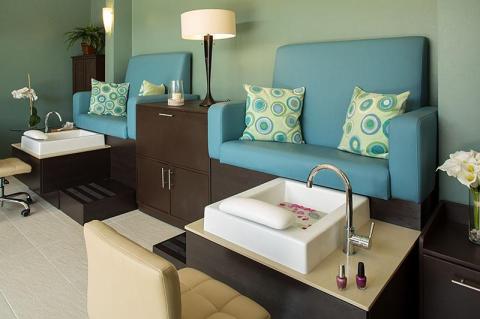 Modern nail salon interior with turquoise pedicure chairs and aqua walls.