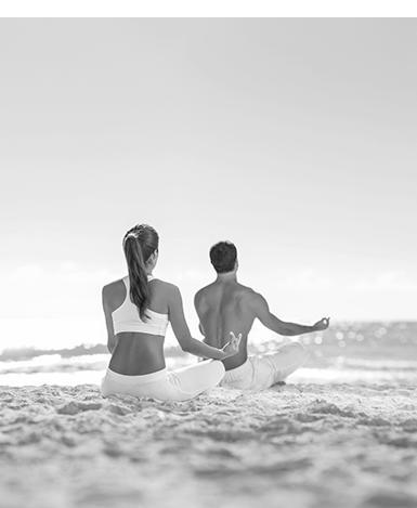 Two people meditating on beach in serene black and white photo