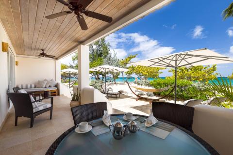 Luxurious beachside patio with furniture and ocean view, perfect for relaxation.