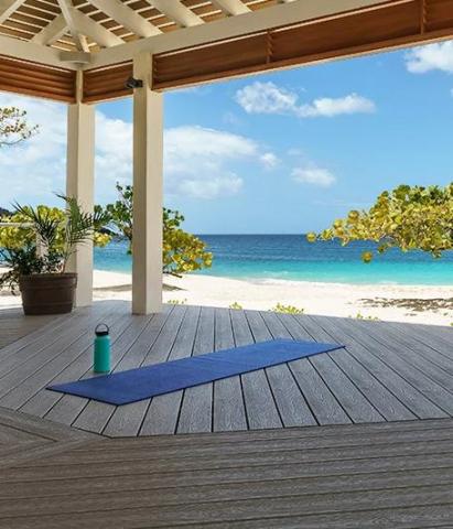 Relaxing beachfront yoga setting with water bottle and tropical trees in view.