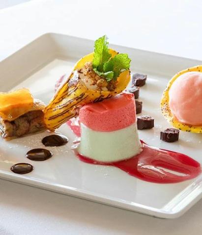 Exquisite dessert plate with layered cake, caramelized banana, and pink sorbet.
