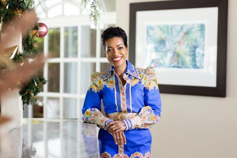 Woman in blue embroidered dress smiling in decorated Christmas room
