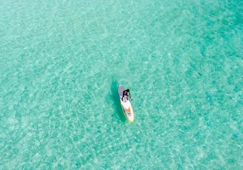 Aerial view of a person paddle boarding on turquoise waters