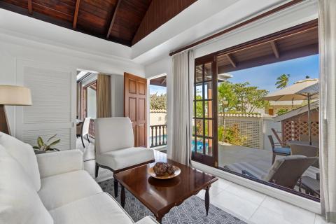 Elegant living room with tropical view and lush garden visible outside.
