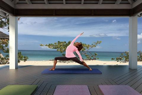 Person doing yoga on mat in serene beach setting under roofed area