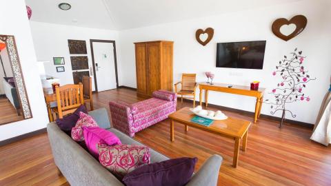 Stylish living room with wooden decor, colorful sofas, and dining area.