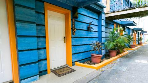 Colorful townhouses with blue siding and orange trims, white doors, and metal decorations.