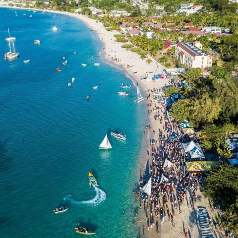 Aerial view of crowded beach with boats and tents, vibrant summer scene