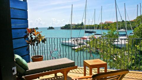 Scenic marina view from terrace with sailboats, islands, and a wooden bench.