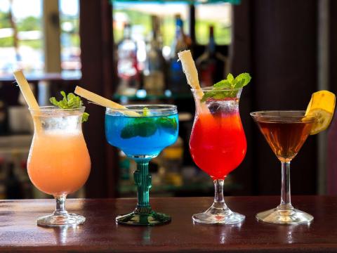 Colorful cocktails in a bar: peach, blue, gradient red, and amber drinks.