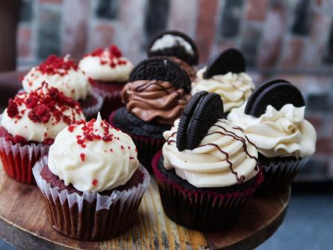 Gourmet cupcakes on wooden board with various toppings and flavors