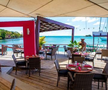 Beachside dining with pink tablecloths and a sea view, under a beige canopy