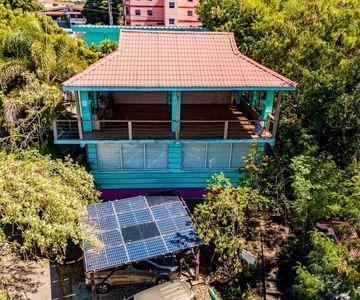 Colorful two-story tropical building with solar panels and lush greenery