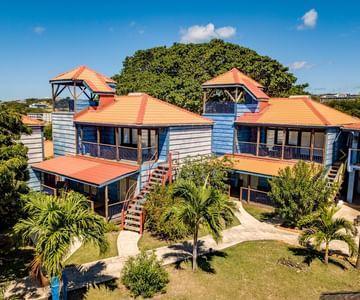 Blue building with red roofs and palm trees on a sunny day