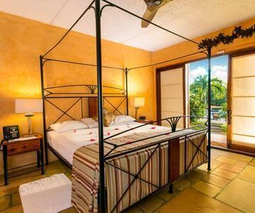 Luxurious tropical bedroom with four-poster bed and lush outdoor view.