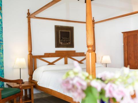 Cozy bedroom with four-poster bed, wooden furniture, and colorful decor