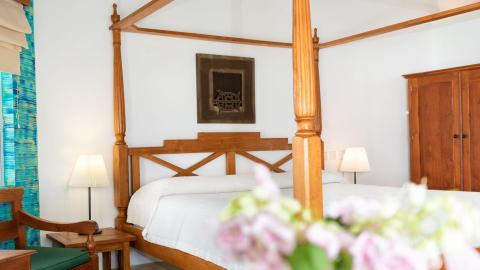 Cozy bedroom with four-poster bed, wooden decor, and vibrant blue-green curtains
