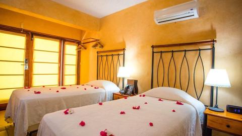 Cozy twin bedroom with romantic red petals and soft lighting for special occasions.