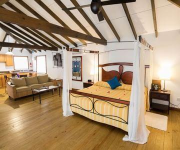 Cozy loft-style bedroom with exposed beams, hardwood floors, and warm lighting.