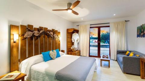 Resort room with large bed, decorative art, and sunset view from balcony
