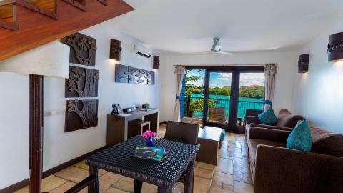 Stylish resort room interior with a view of water and lush greenery.