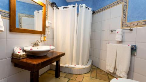 Compact bathroom with white sink, mirror, shower area, and decorative blue accents.