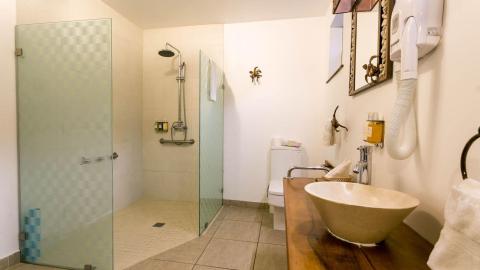 Modern bathroom with glass shower, wooden countertop, and artistic fixtures