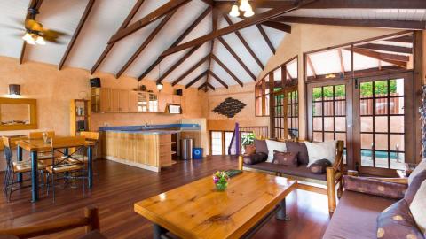 Spacious room with vaulted ceiling, wooden beams, and a cozy kitchen-dining area.