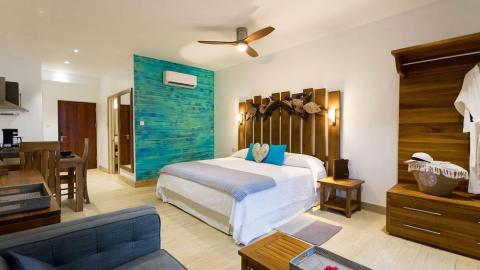Modern hotel room with blue sofa, wooden decor, and double bed