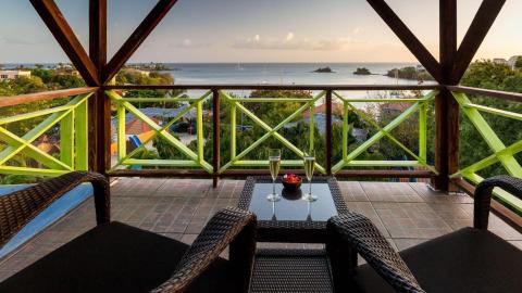 Scenic balcony view with gazebo, rattan chairs, fruits, and coastal backdrop