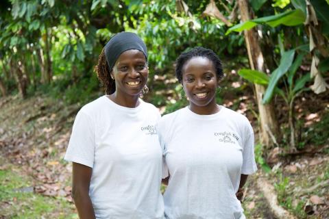 Two women in Crayfish Bay Organics tees smiling in a lush garden setting
