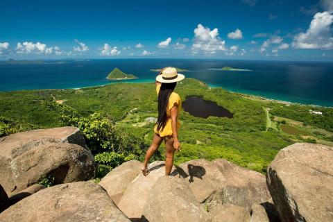 Woman in yellow dress enjoys scenic coastal view from hilltop