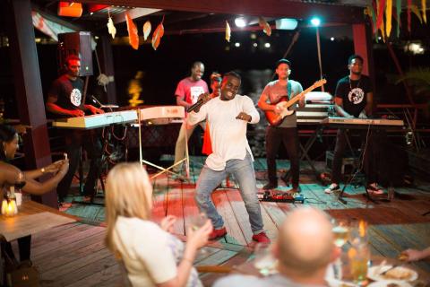 Nighttime pier concert with lively dancing man and live band under string lights