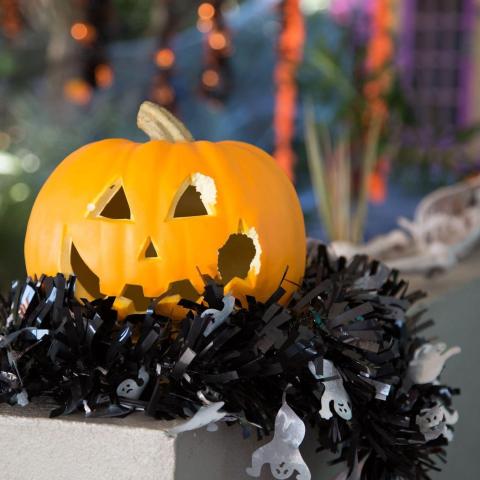 Carved pumpkin with bite marks and ghost-shaped garland in garden.