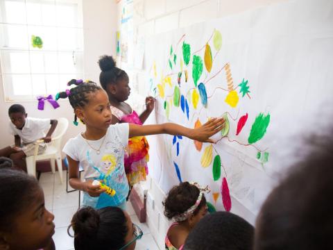 Children coloring leaf shapes on paper in a sunny classroom
