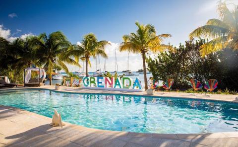 Tropical Grenada resort with pool, palm trees, and ocean view with boats