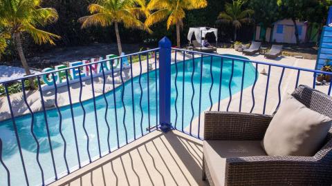 Sunny pool area with deck chairs, palm trees, and colorful sign