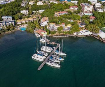 Aerial view of sailboats at a pier in a tropical coastal area with lush greenery