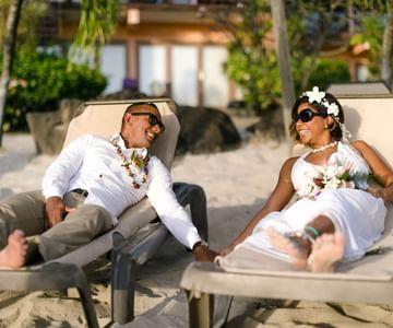 Joyful beach wedding with couple in white attire and floral accessories
