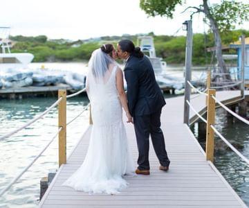 Bride and groom kissing on dock at marina on wedding day