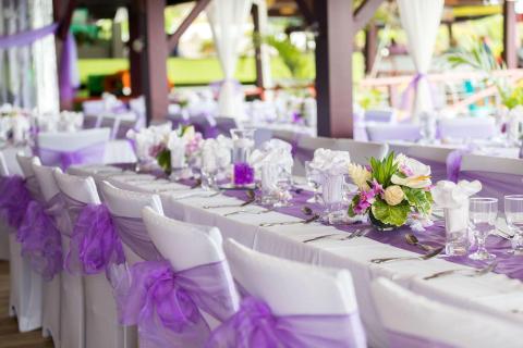Elegant outdoor wedding setup with white and purple decor, floral accents