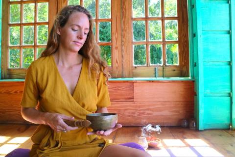 Woman meditating in yellow robe with incense in serene, green-themed room