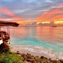 Barbados Sunset View with Azure Waters and People A vibrant sunset over a Barbados beach with people